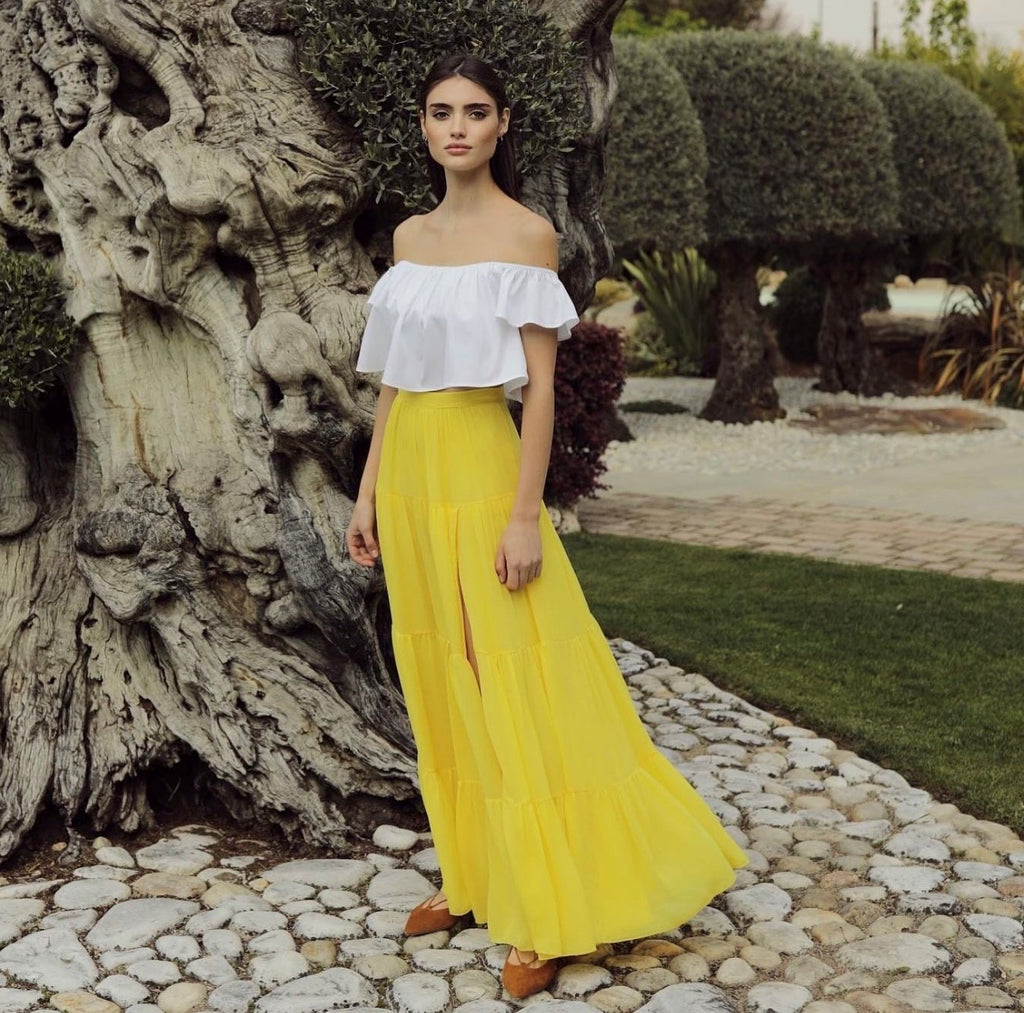 modella indossa top estivo bianco in cotone su gonna lunga gialla con spacco in pura seta firmata Celeste Pisenti 