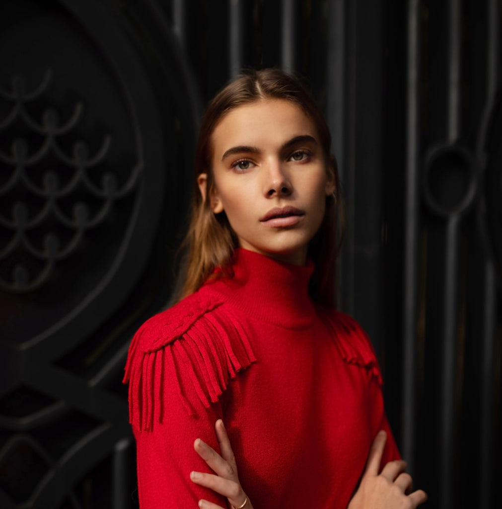 La modella indossa la maglia cashmere rossa Napoleon con spalle intarsiate con frange decorative della stilista Celeste Pisenti